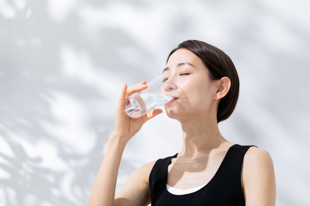 水を飲む黒いタンクトップを着た女性