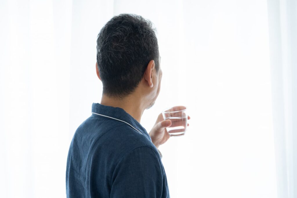水を持ったグラスを持つ男性の後ろ姿