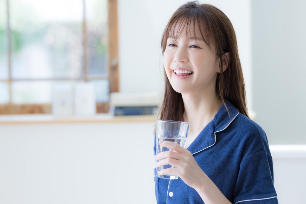 水の入ったグラスを持って笑う女性