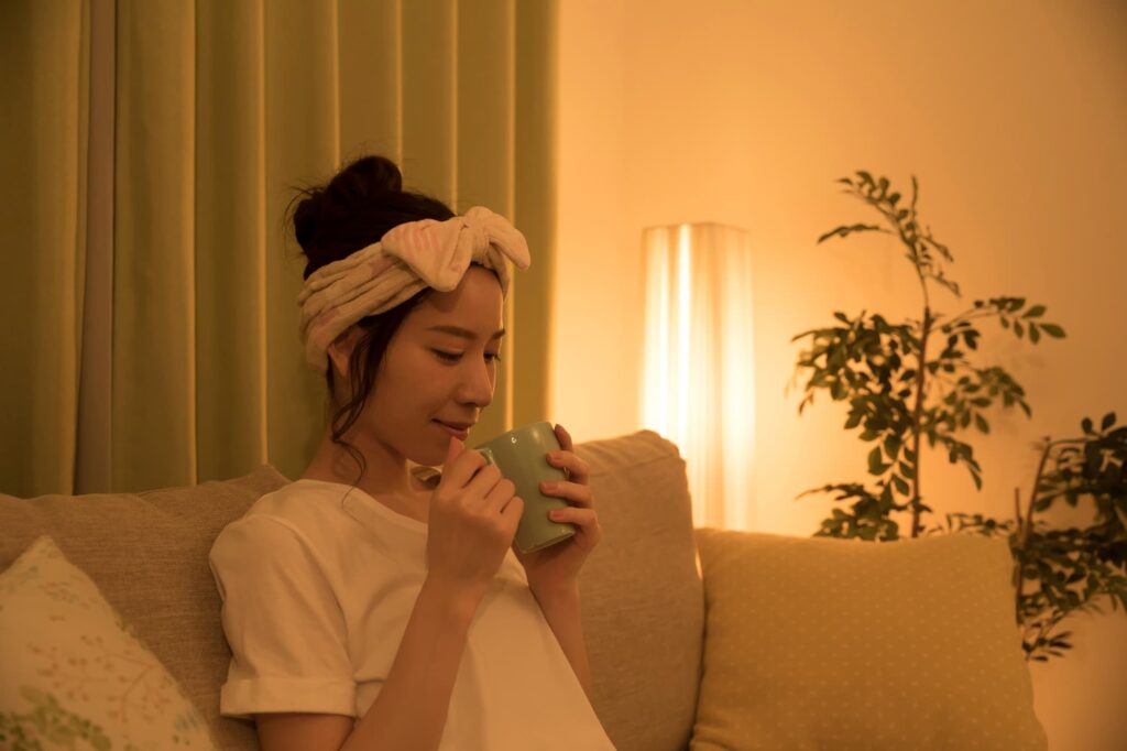 ソファで飲み物を飲む女性