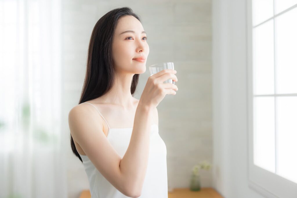 窓辺で水を飲む女性