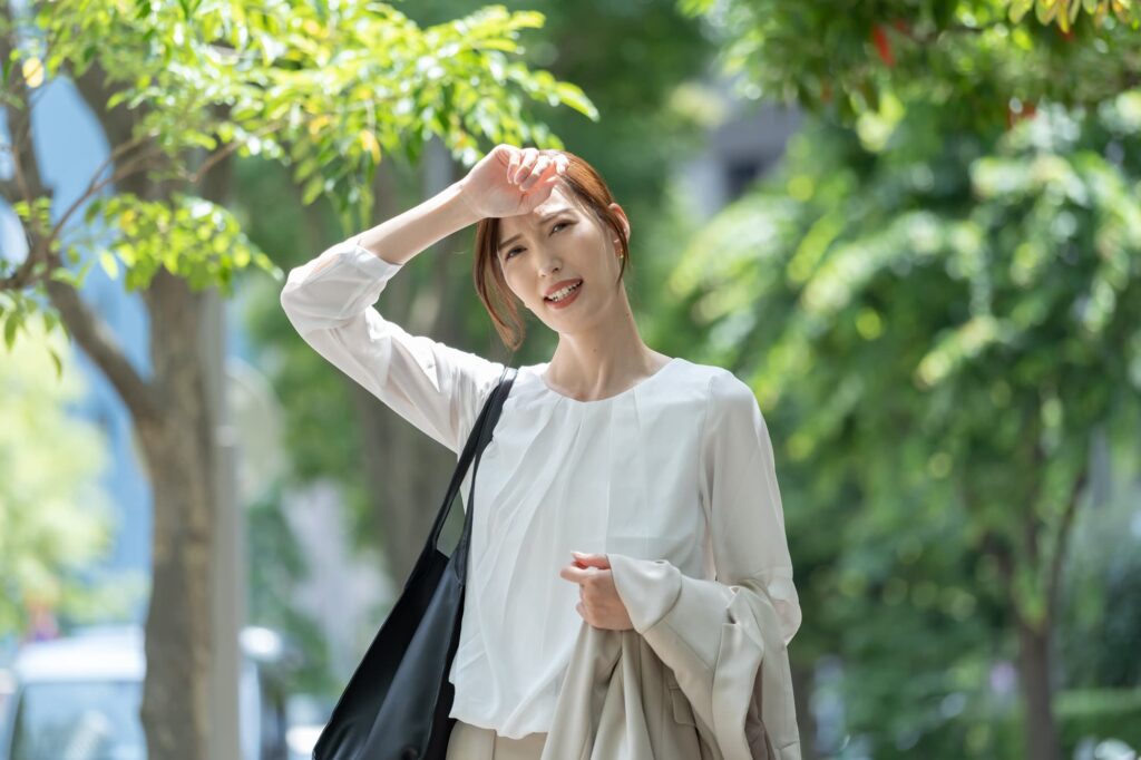 外で汗をぬぐう女性